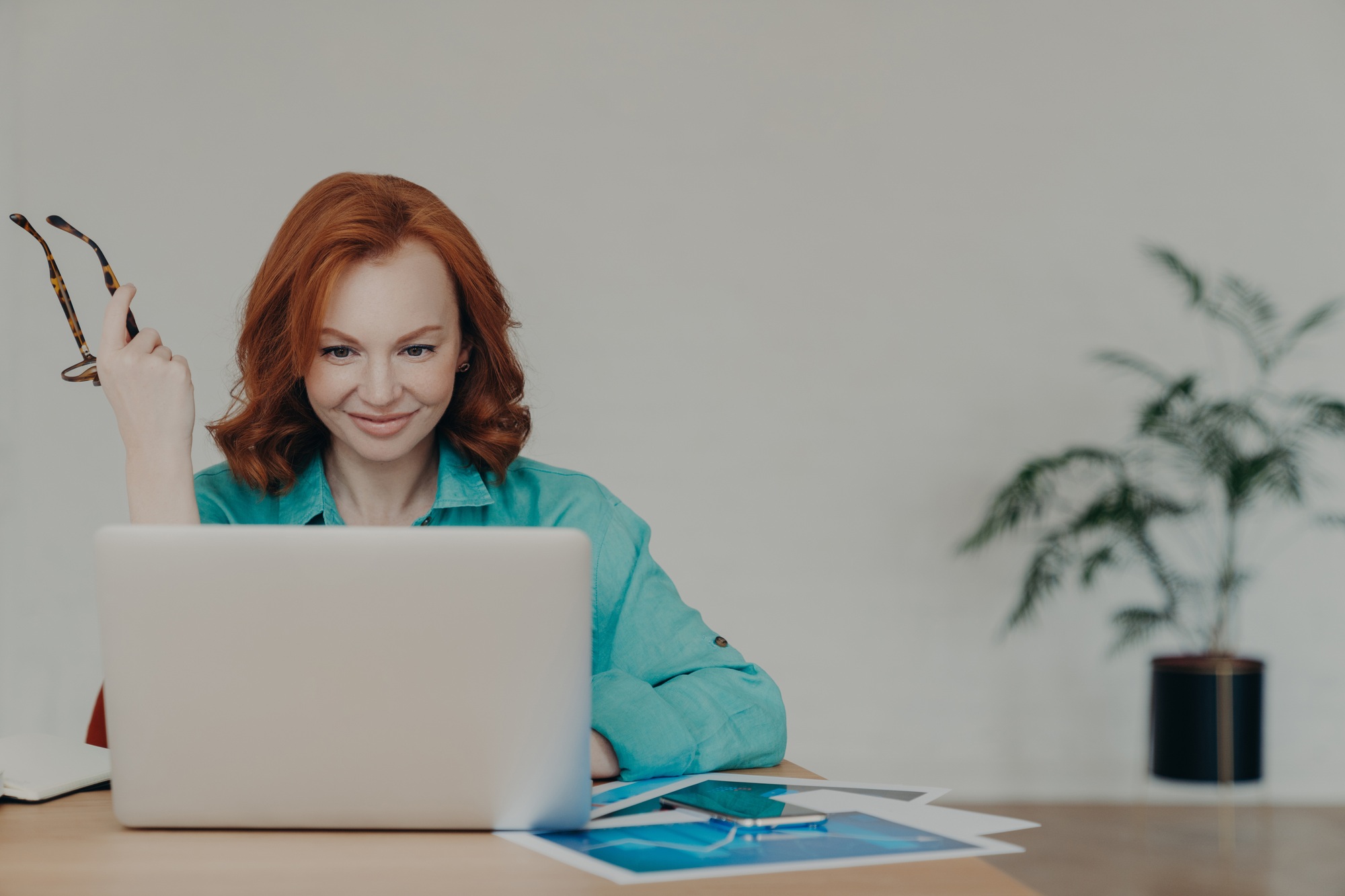 Female financial analyst prepares research, works on laptop computer, consults clients online.
